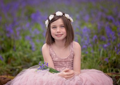 Girl wearing pink tulle dress sitting in the Northamptonshire bluebells