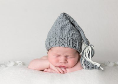 Baby boy with grey hat on white background for newborn photoshoot in Northampton