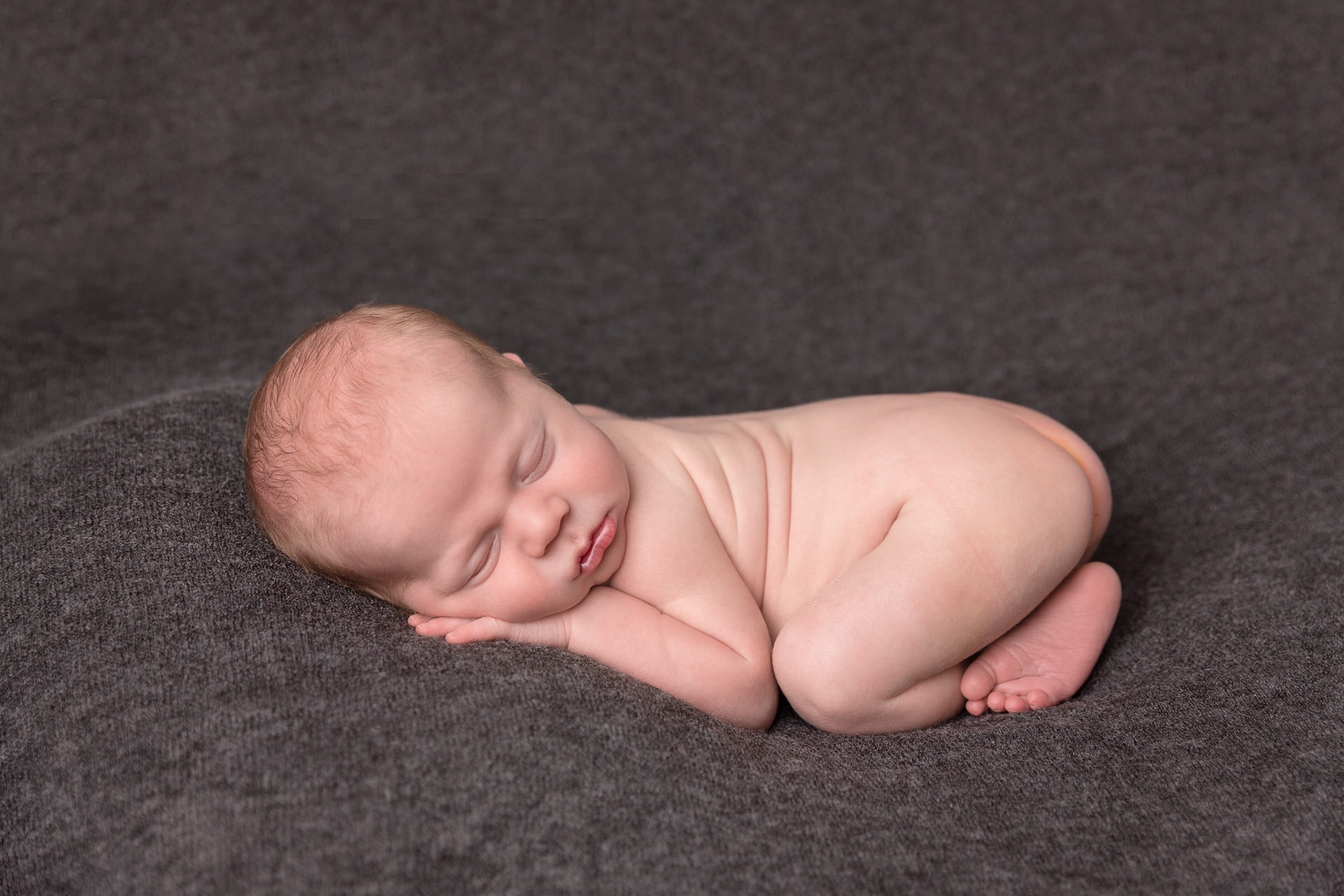 Baby boy on grey background for newborn photoshoot in Northampton