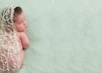 Baby girl draped in lace on green background