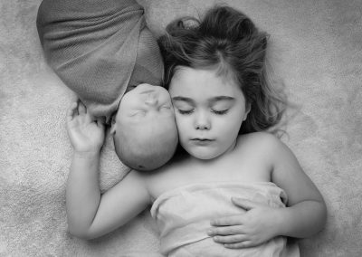 Baby boy with big sister asleep for newborn photoshoot in Northampton