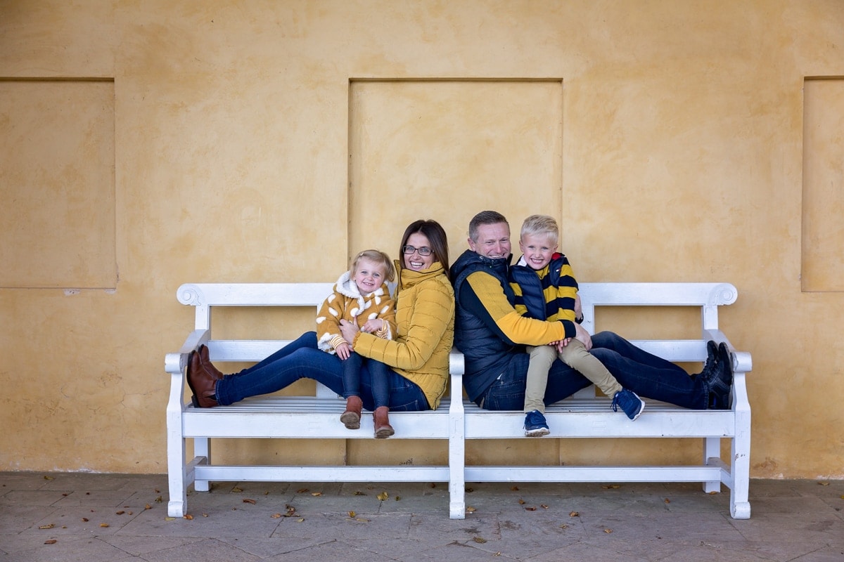 Family of 4 sitting on a bench in outdoor Northampton photoshoot