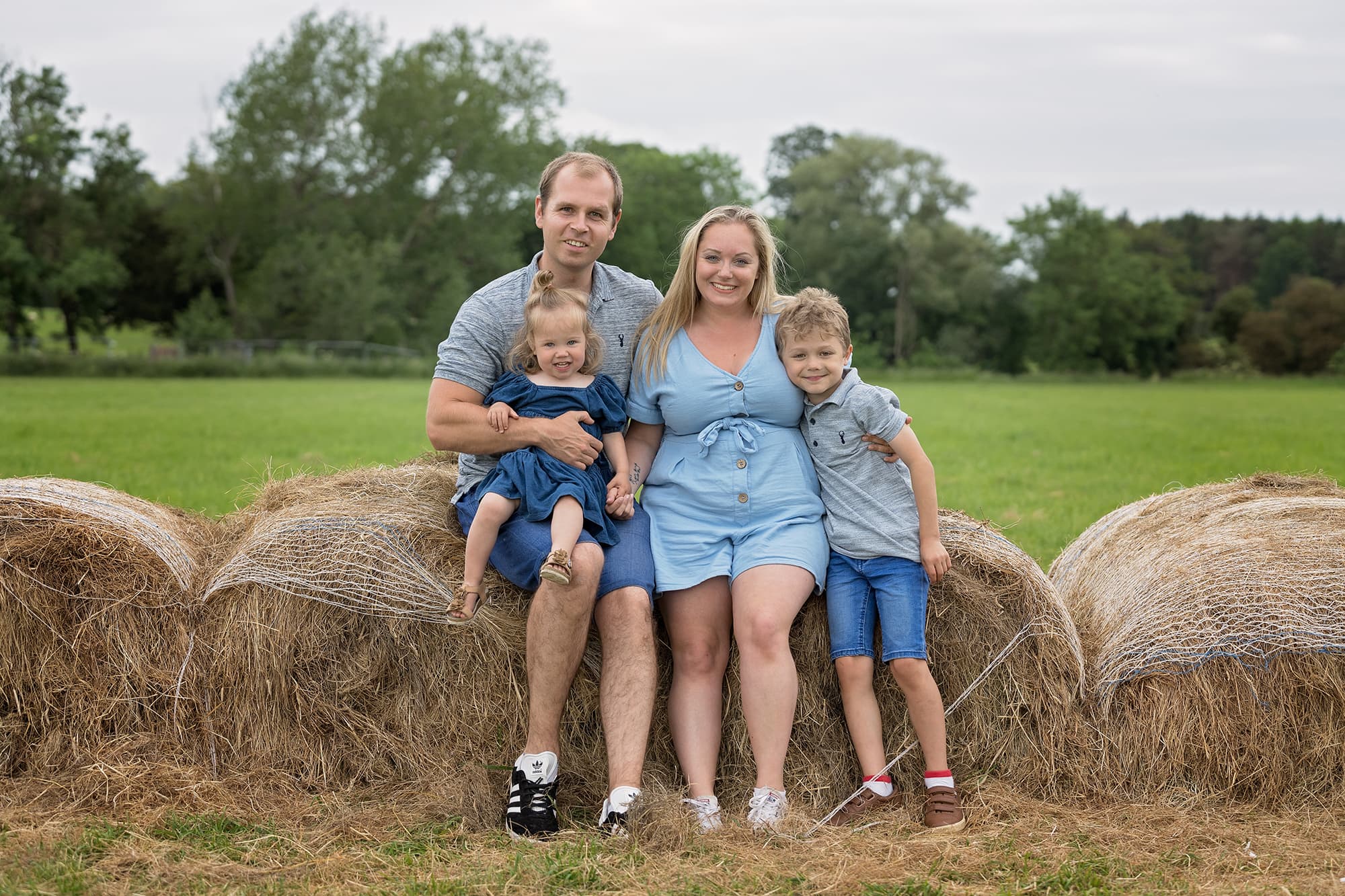 Family photoshoot in Towcester - family of four sitting on a hay bale
