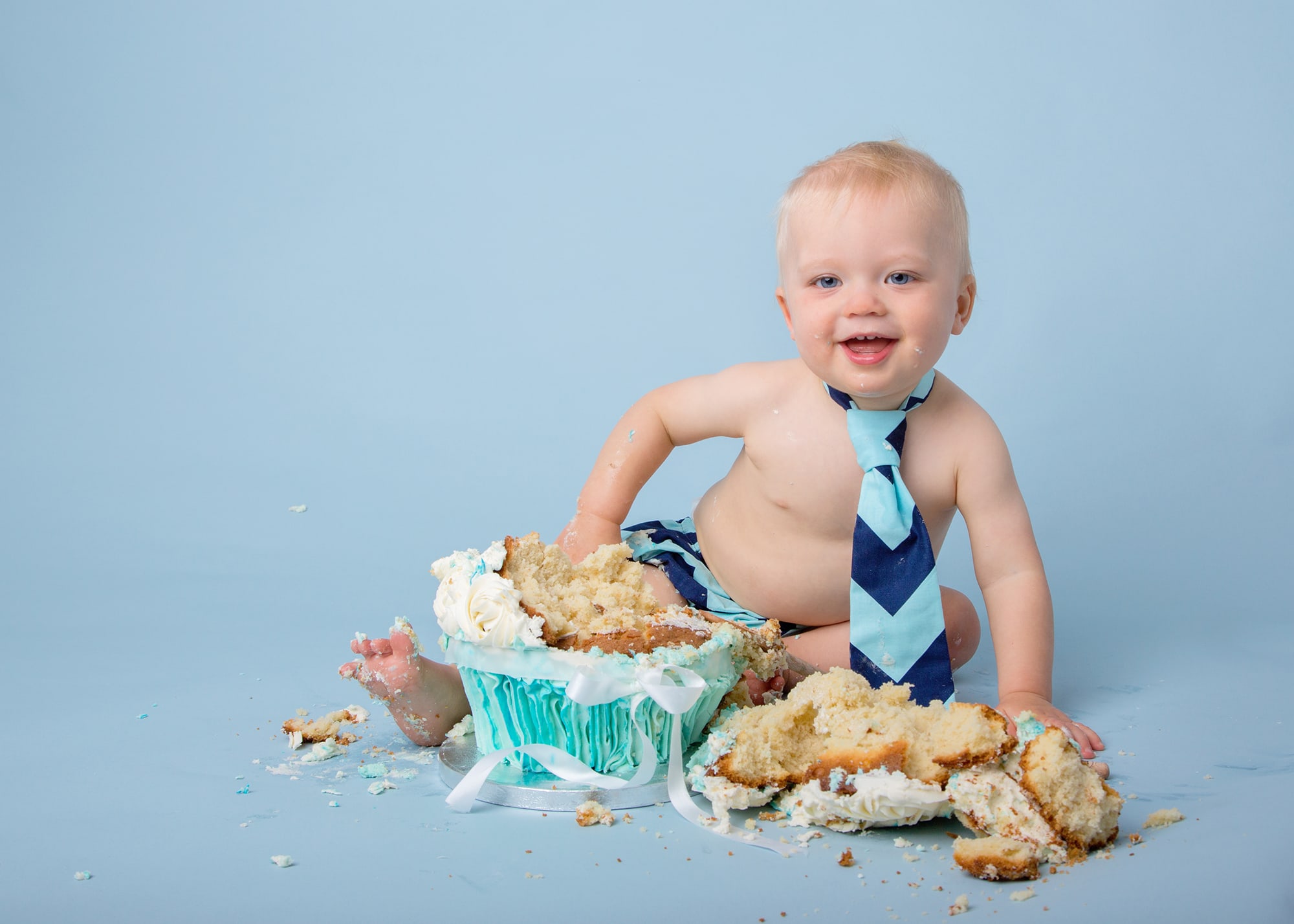 cake smash photoshoot with baby boy on a blue background with cake