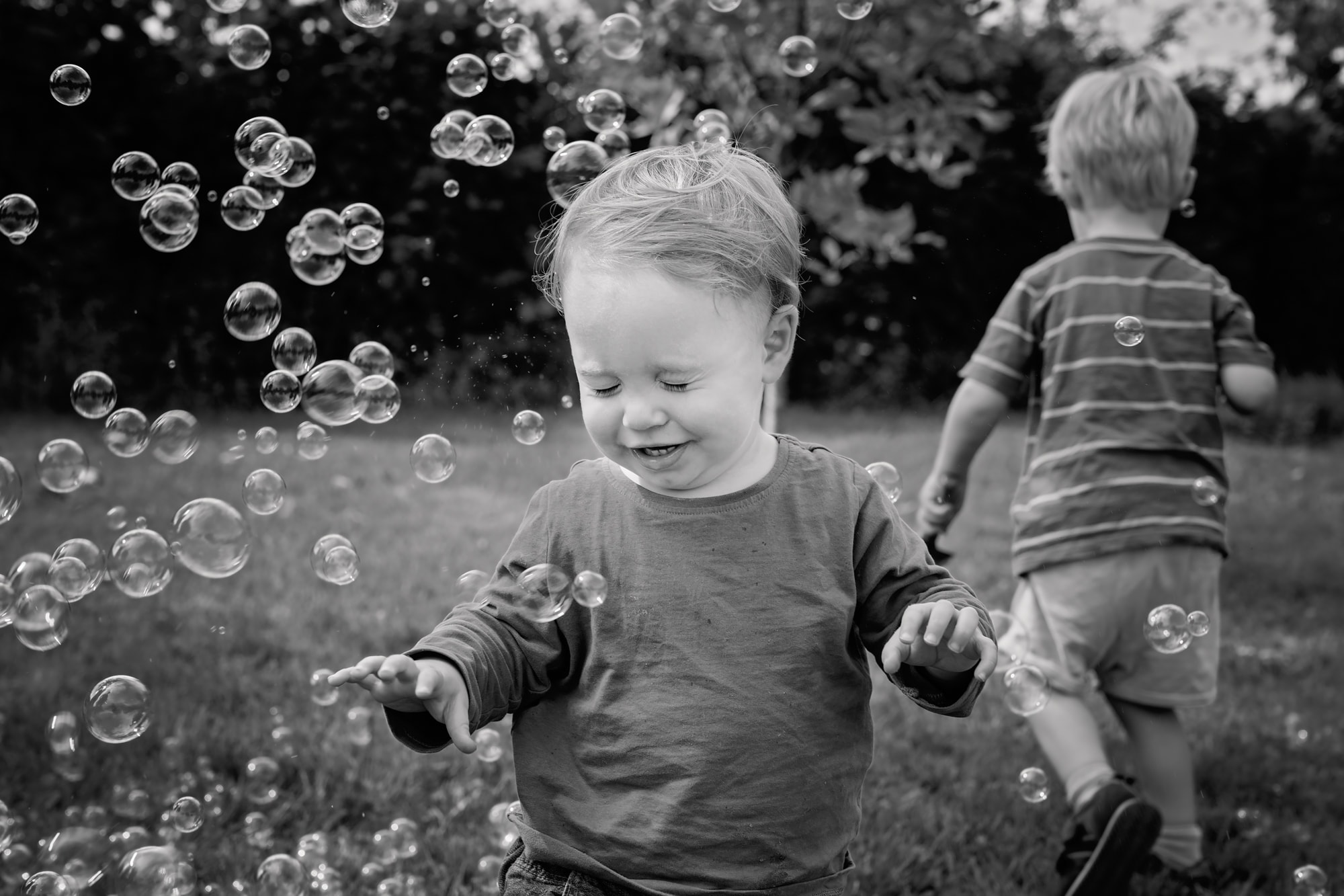 Black and white photograph of a little boy popping bubbles