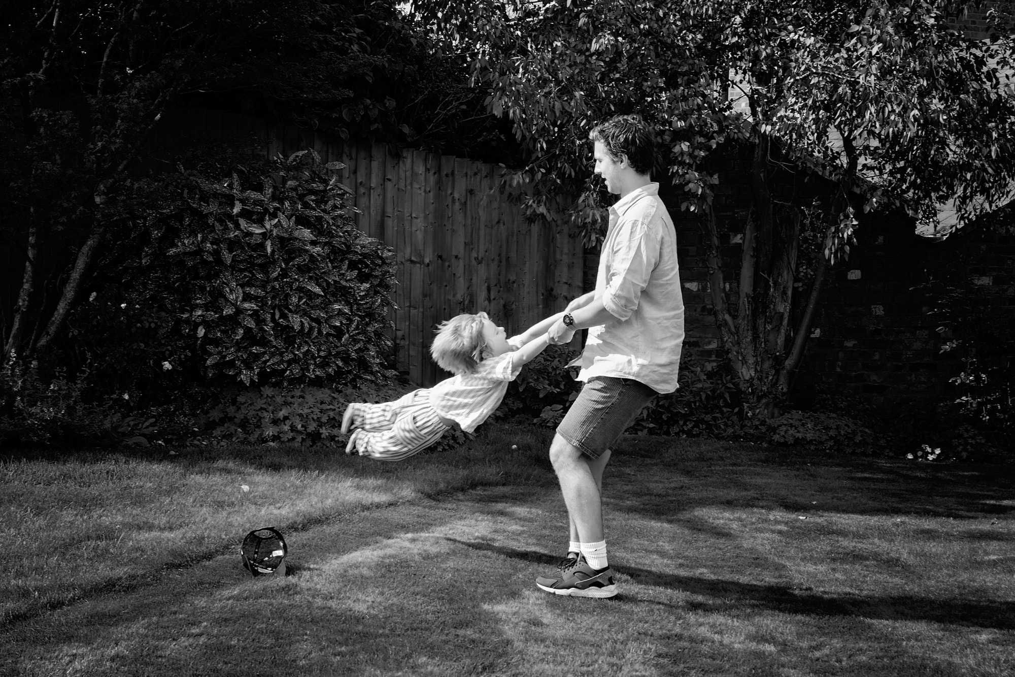 black and white photograph of a dad swinging his little boy in circles
