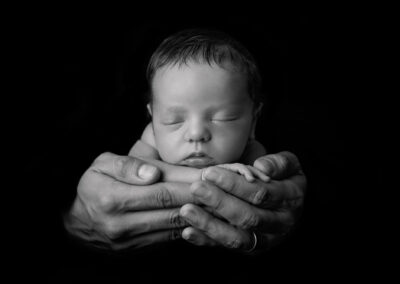 newborn in dad's hands in black and white