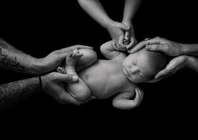 newborn in family's hands in black and white